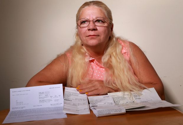 Carol Ray, of south St. Louis County, poses with two unpaid tickets, a warning and a failure to appear/pay notice from two municipalities on Friday, Sept. 19, 2014. She says she cannot afford to pay them, and she has skipped court dates for each of them for fear of being arrested. (Photo from St. Louis Post-Dispatch)
